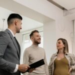 A couple consults with a real estate agent indoors, showcasing an exemplary customer service moment.