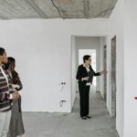 A couple explores an unfinished apartment with a real estate agent, considering property purchase options.