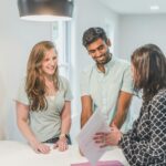 A smiling couple discusses real estate options with an agent inside a modern home.